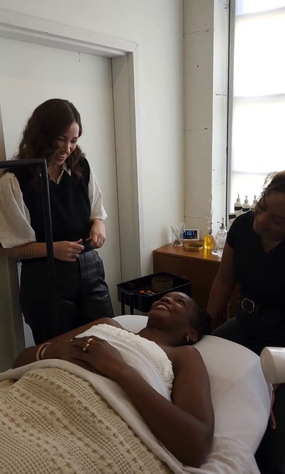 Kelly coaching an esthetician through a hands-on facial treatment