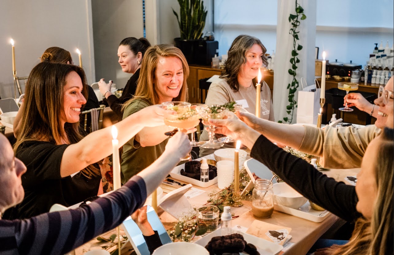 Guests raising a toast at a candlelit TEMPLE Skin Party around a long table