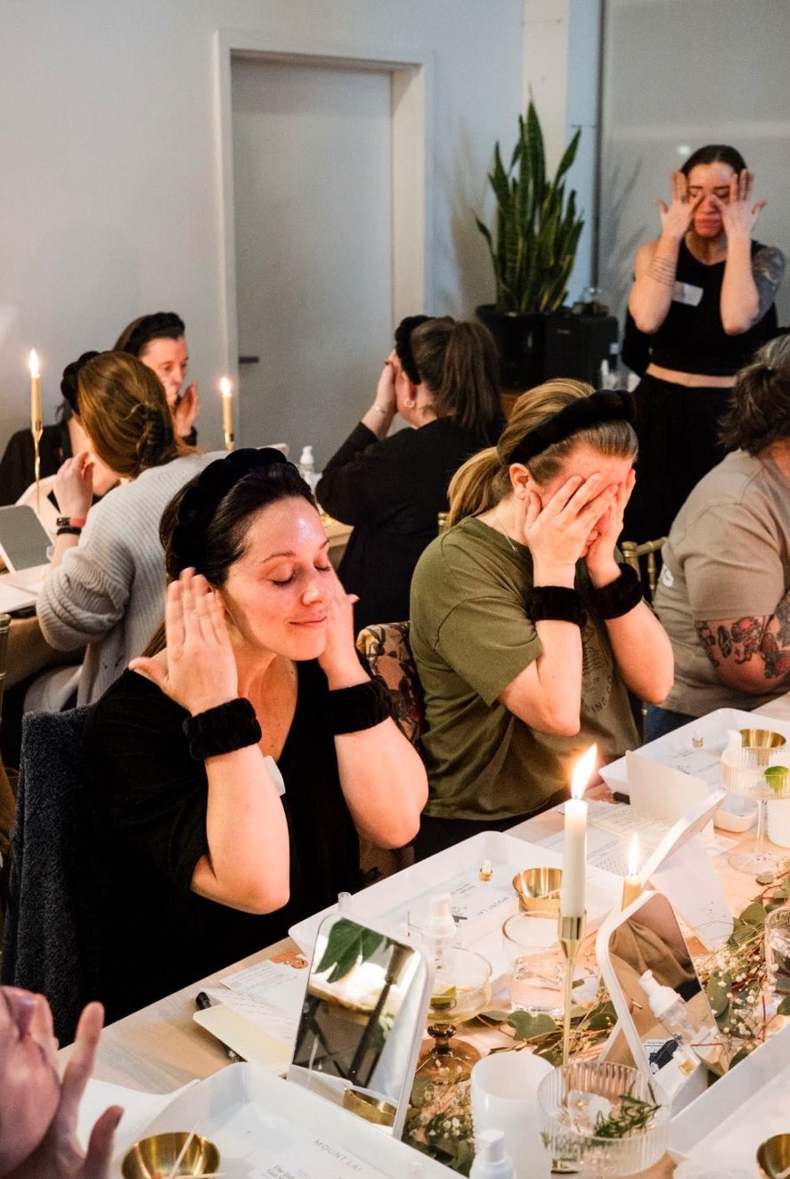 Skin Party guests practicing facial massage at a candlelit table